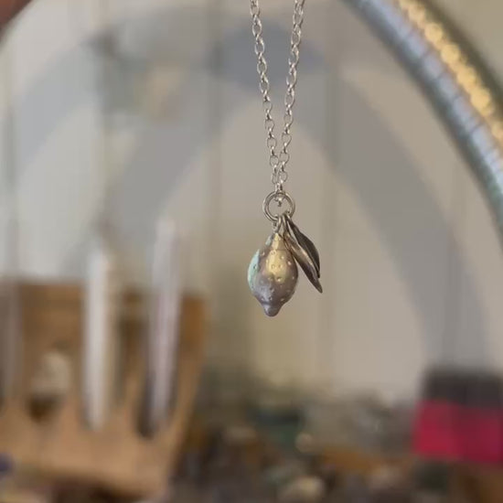 Image shows a Lemon pendant, the lemon has been handcrafted from sterling silver and sits among two silver leaves, hanging from a silver chain. 
